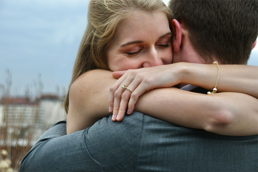 Happy couple that have just got engaged. They are hugging The woman has a diamond ring on her finger.